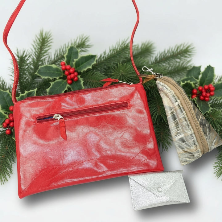 Red crossbody bag with a keychain and small pouch on a dark surface