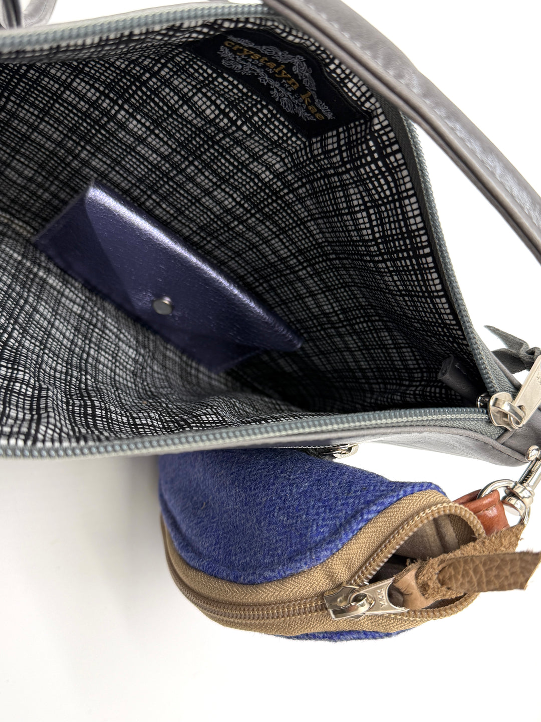 Close-up of a gray handbag with a blue pouch inside on a white background