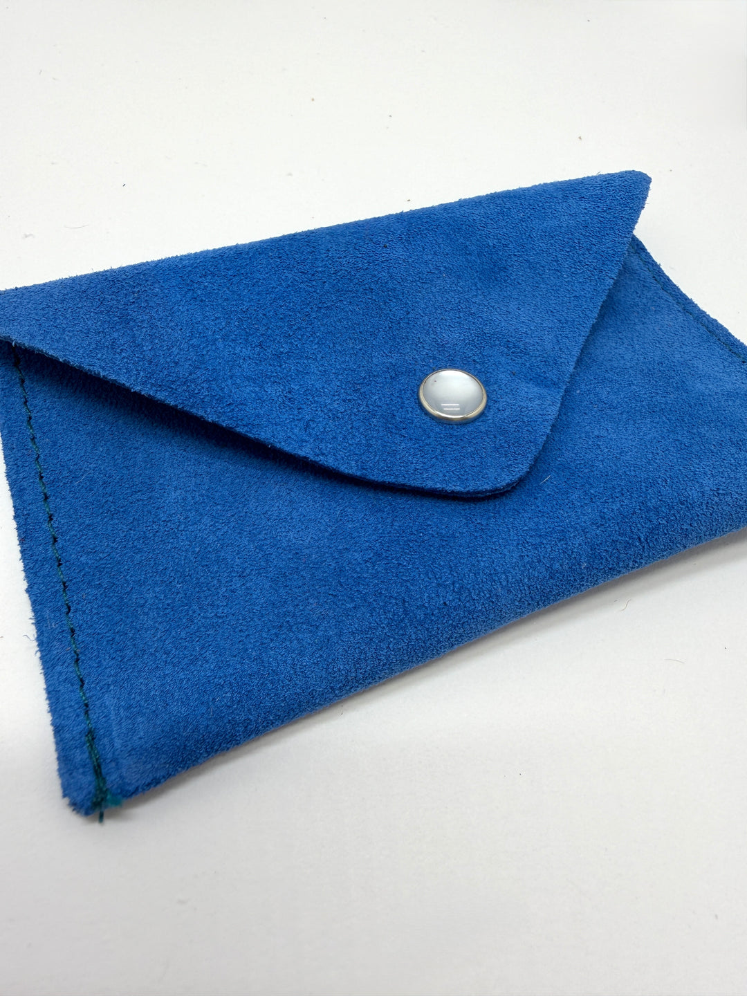 Blue suede clutch with a silver button on a white background #color_blue-suede