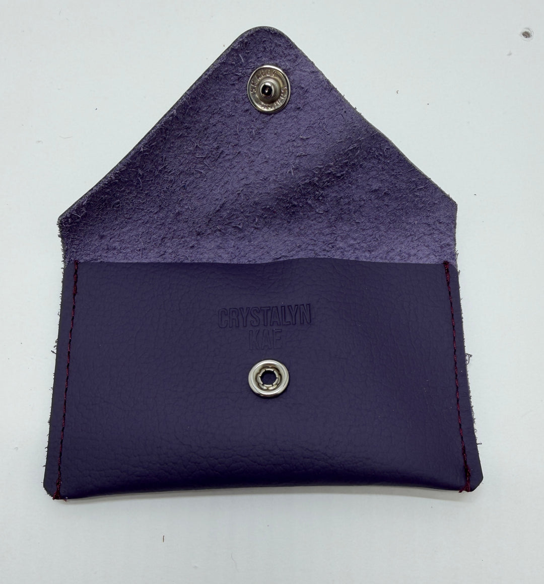 Purple leather wallet with metal buttons on a white background #color_plum
