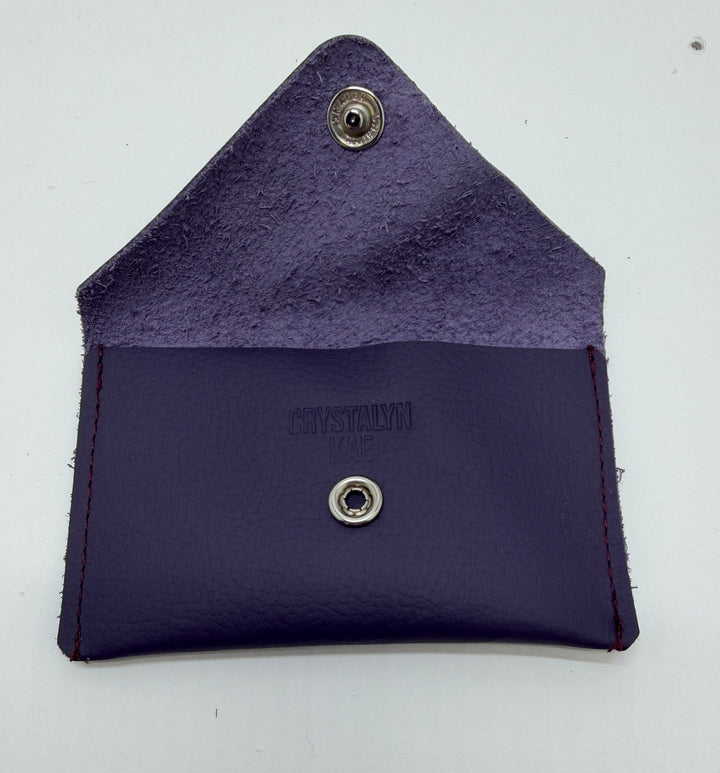 Purple leather wallet with metal buttons on a white background #color_plum