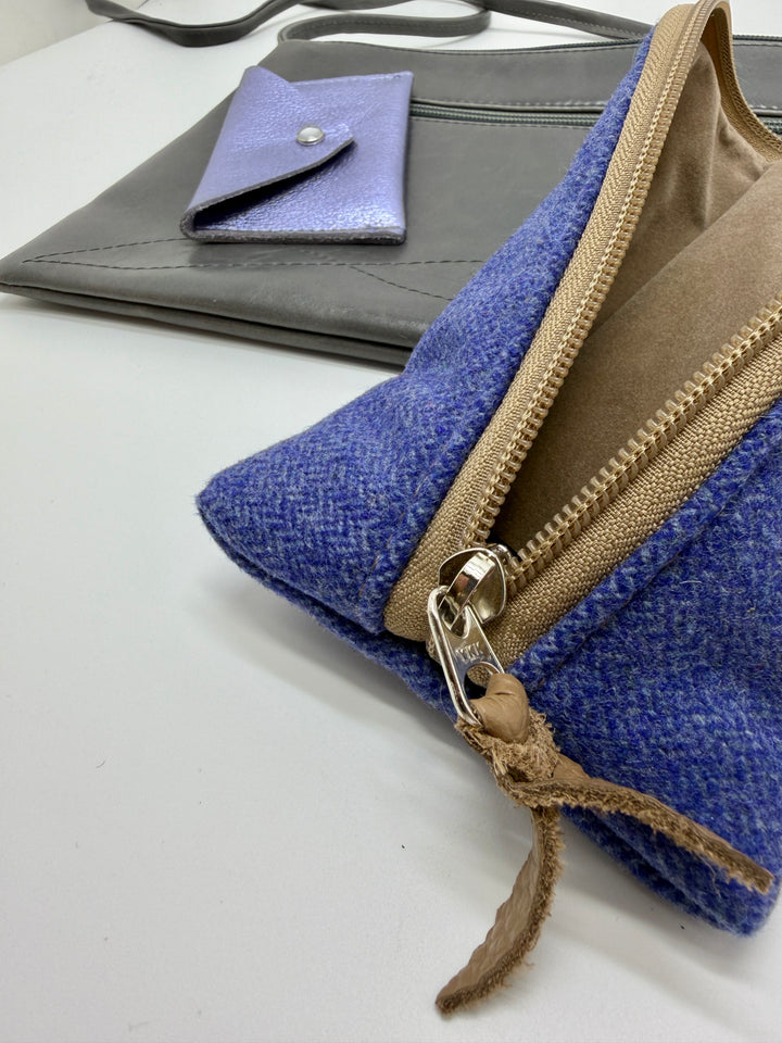 periwinkle blue pouch with brown zipper and drawstring on a white surface.