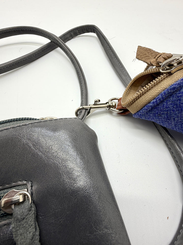 Close-up of a black leather handbag with a blue strap on a white background