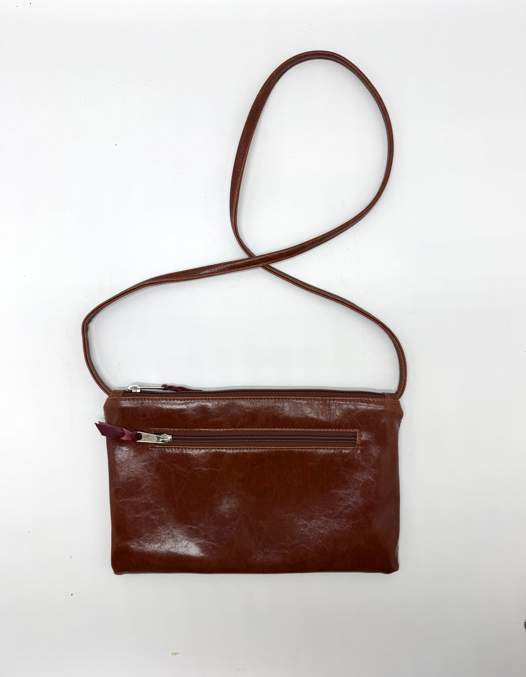 Brown leather crossbody bag on a white background#color_sky-arches-red-purple