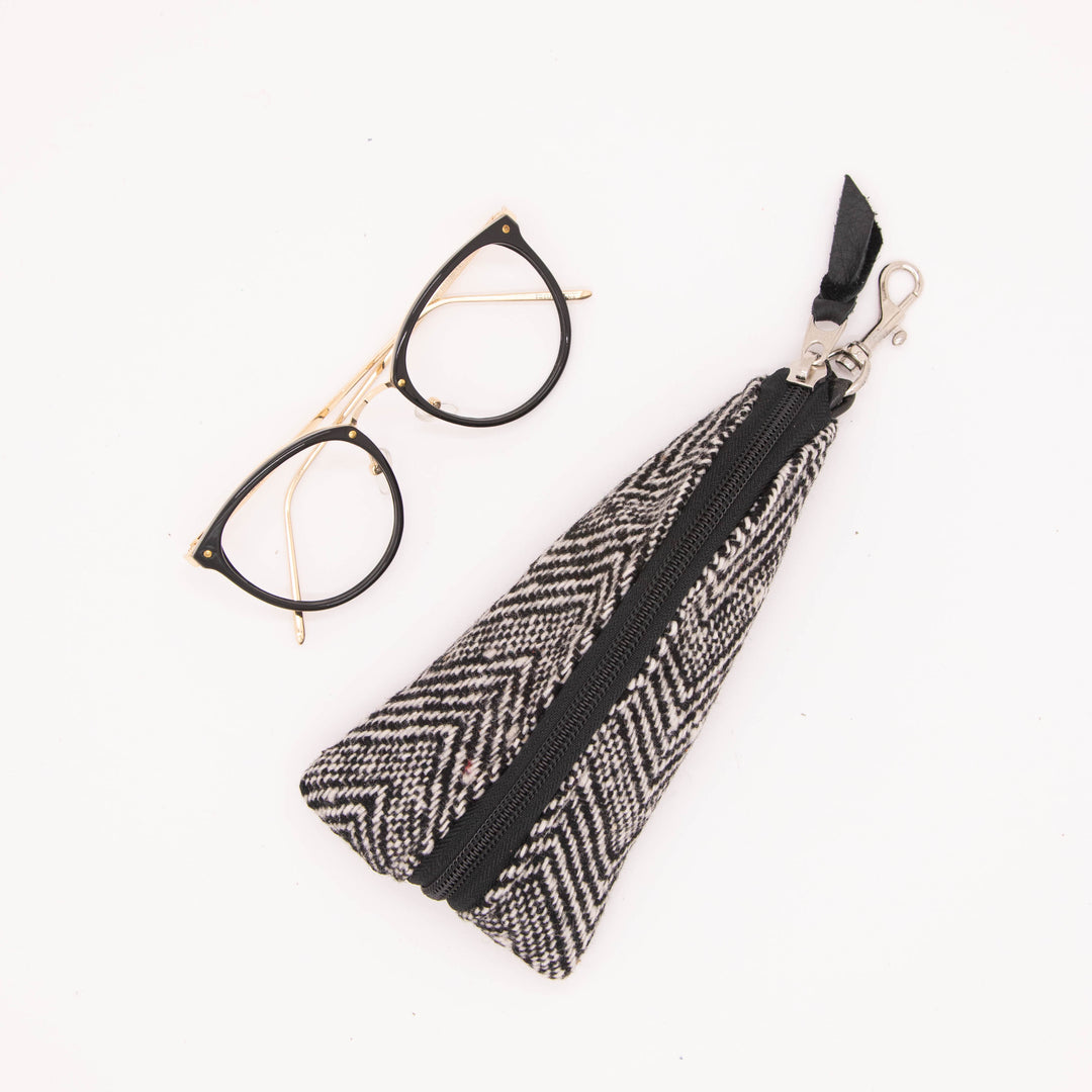 Black and white patterned pouch with a zipper and glasses on a white background#color_crosswind-chevron