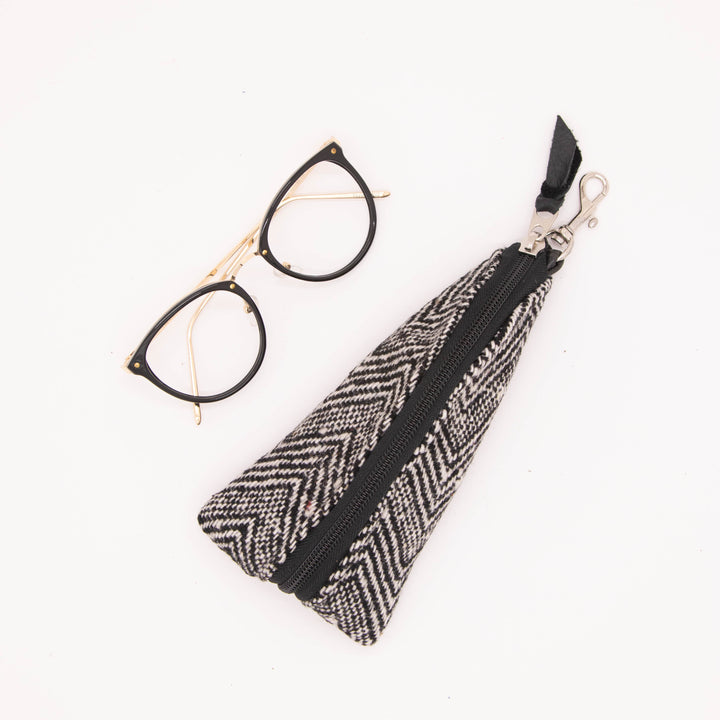 Black and white patterned pouch with a zipper and glasses on a white background#color_crosswind-chevron