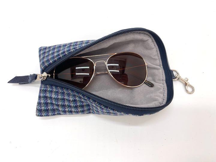 Sunglasses in a blue herringbone pouch on a white background#color_navy-highland-check