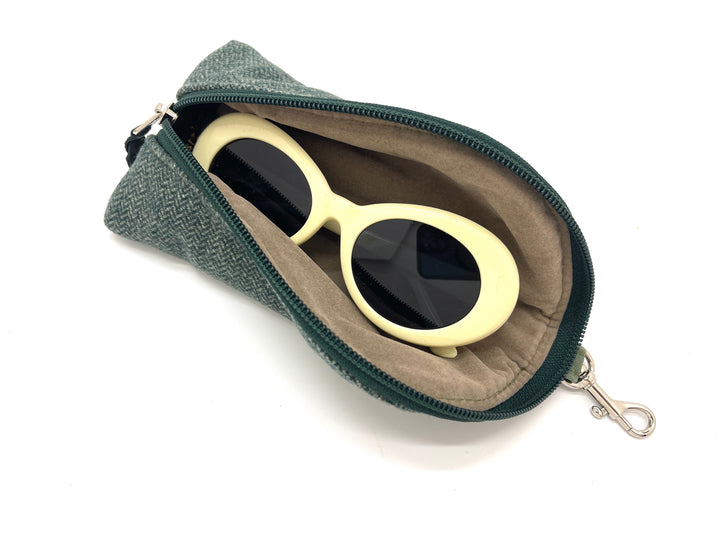 Sunglasses with gold frame and black lenses in a green case on a white background#color_navy-highland-check