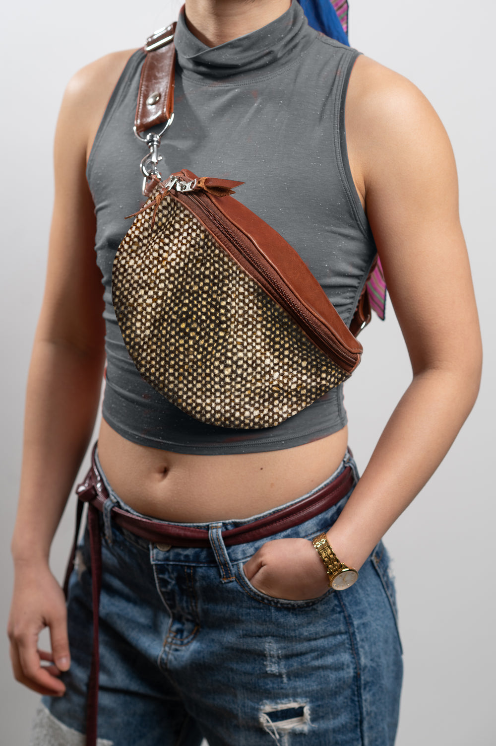 Person wearing a studded brown bag over one shoulder against a plain background#color_beatnik-tweed