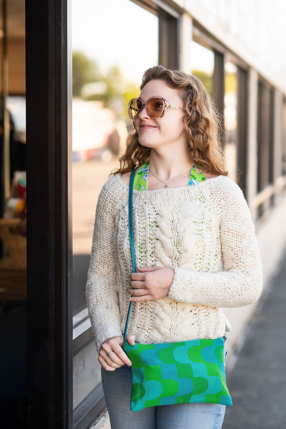 Woman holding a green and blue patterned bag outdoors#color_sky-arches-teal-green