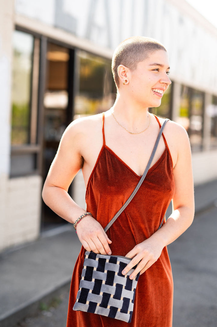 Woman in a red dress holding a patterned bag outdoors#color_navy-basketweave