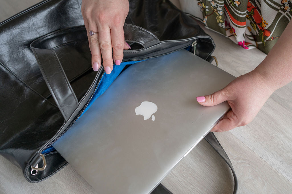 Person holding a 15"  laptop with an Apple logo inside a black bag.