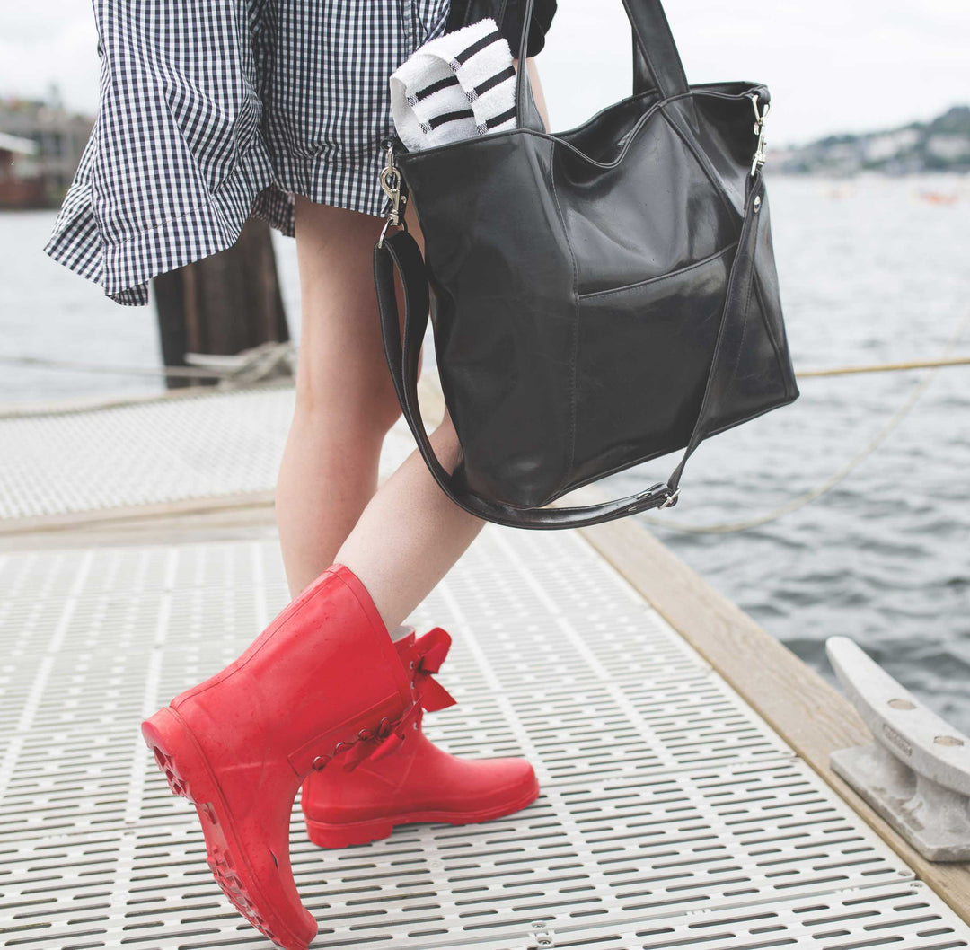 Person wearing red boots and a black handbag by a waterfront